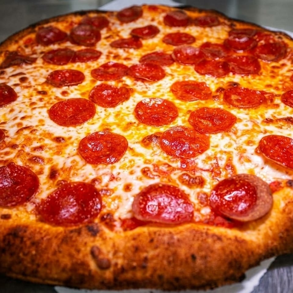 A freshly baked pepperoni pizza with melted cheese and a golden-brown crust on parchment paper.